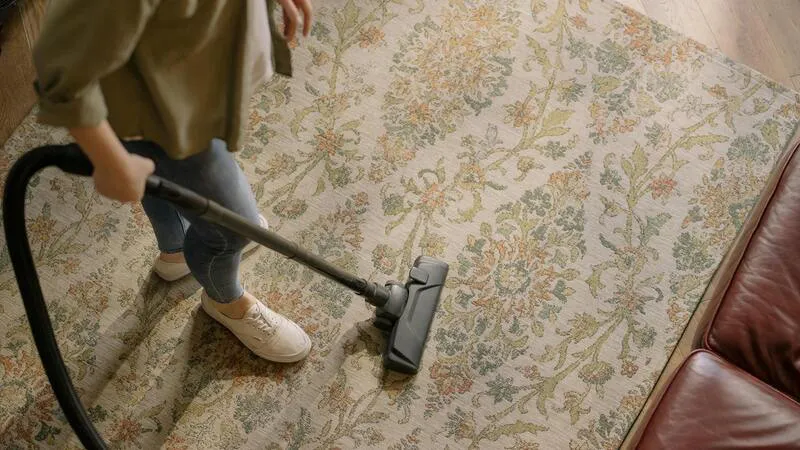 Cleaner vacuuming carpeted flooring to remove debris